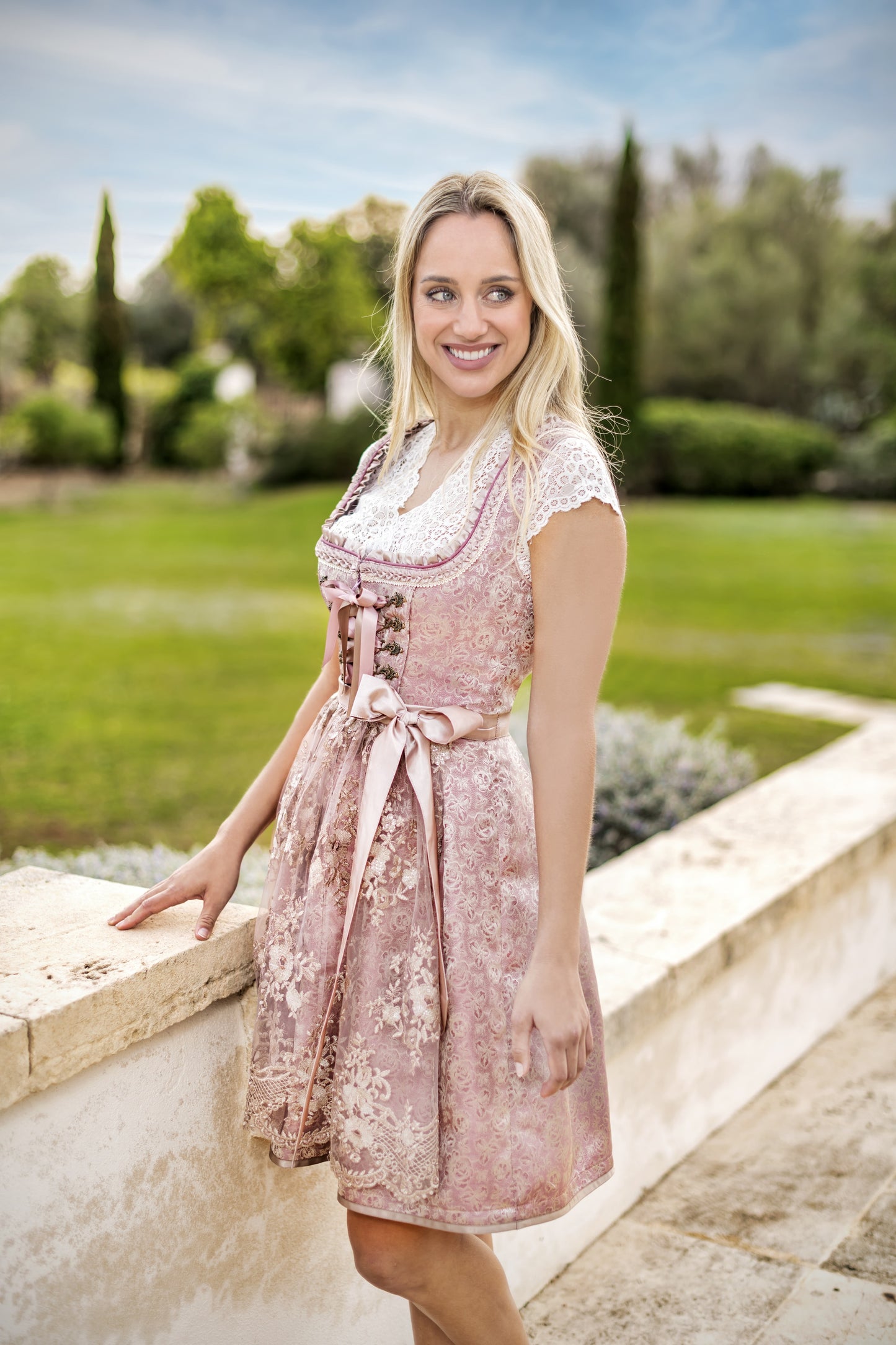 A woman wearing a dirndls and a white short-sleeved dirndl blouse with a V-neckline and lace detailing.