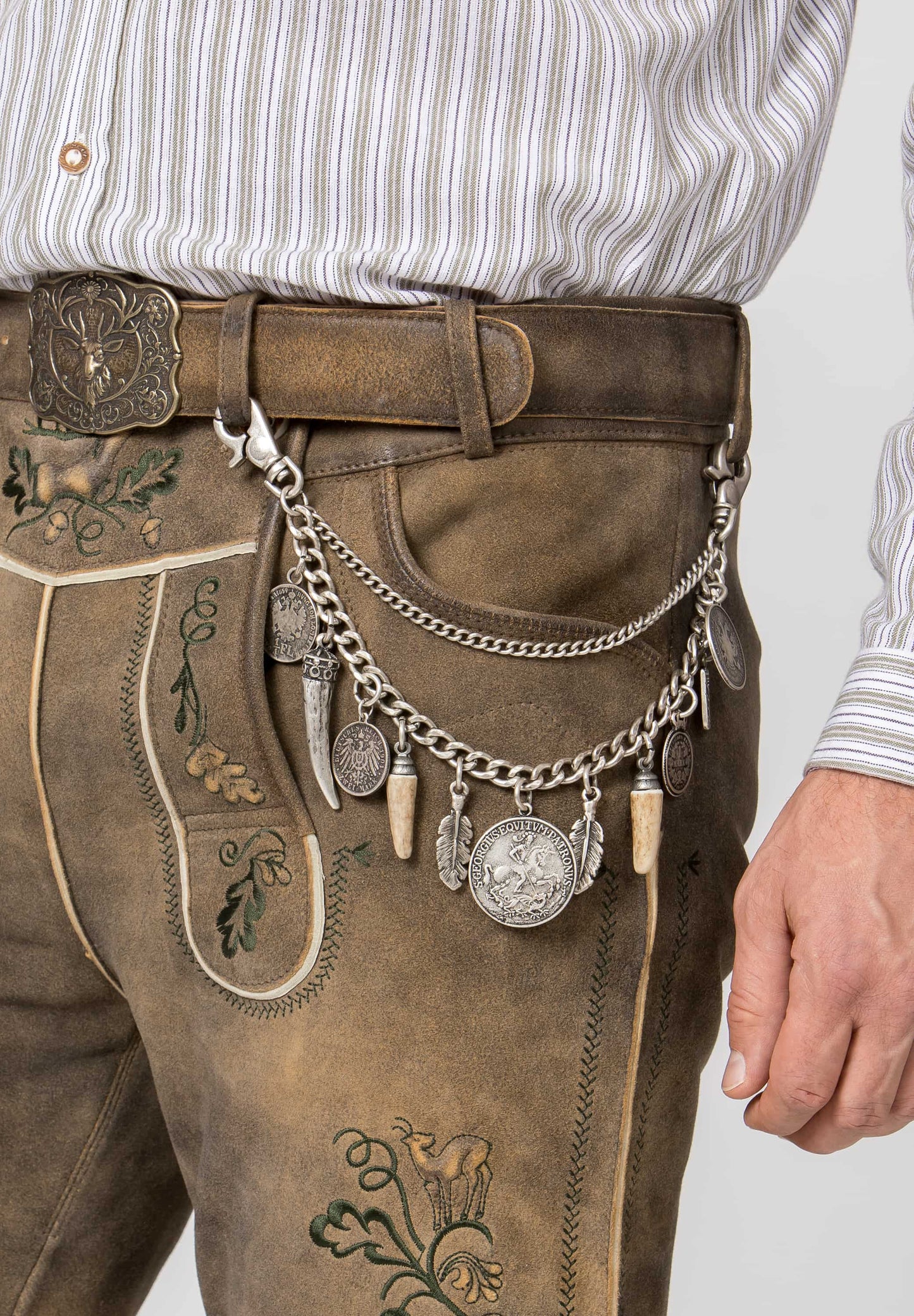a close up of Man wearing traditional Bavarian lederhosen Silver charivari to wear with lederhosen with various charms on a white background with a white shirt on a white background