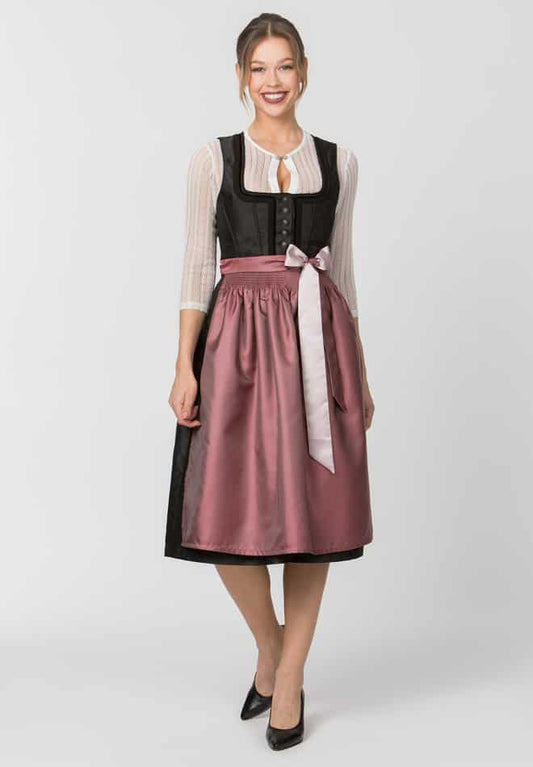 Woman wearing a traditional outfit with a black top and pink skirt on a white background