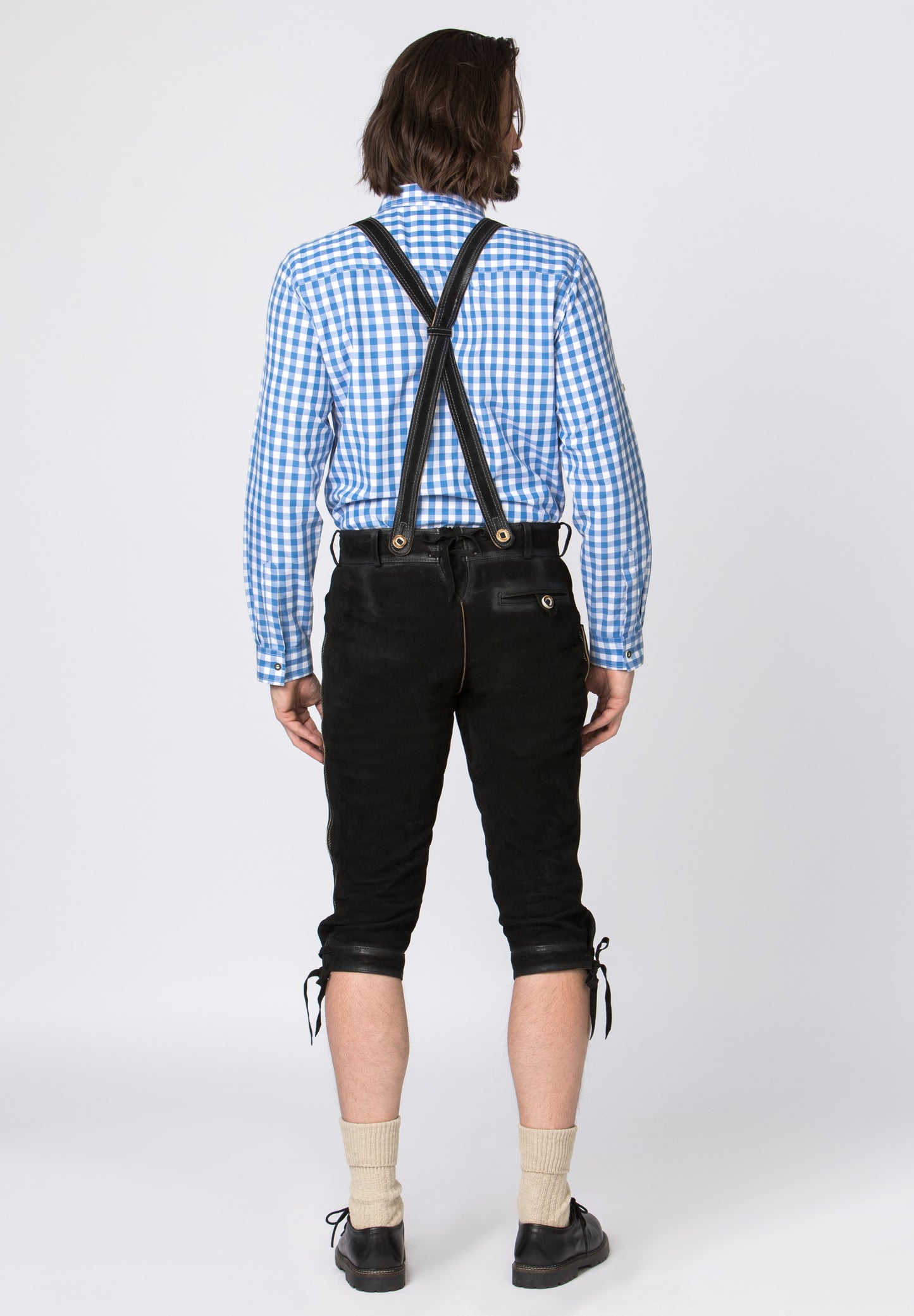 A man wearing traditional leather bundhosen with decorative stitching and suspenders, commonly seen at Bavarian festivals and Oktoberfest.