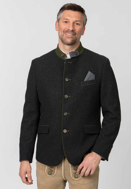 Man wearing a black jacket with green collar and beige pants on a white background
