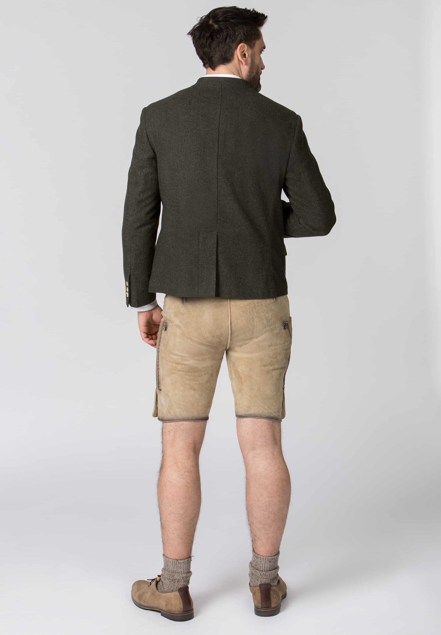 Man wearing a dark green blazer and beige shorts on a white background