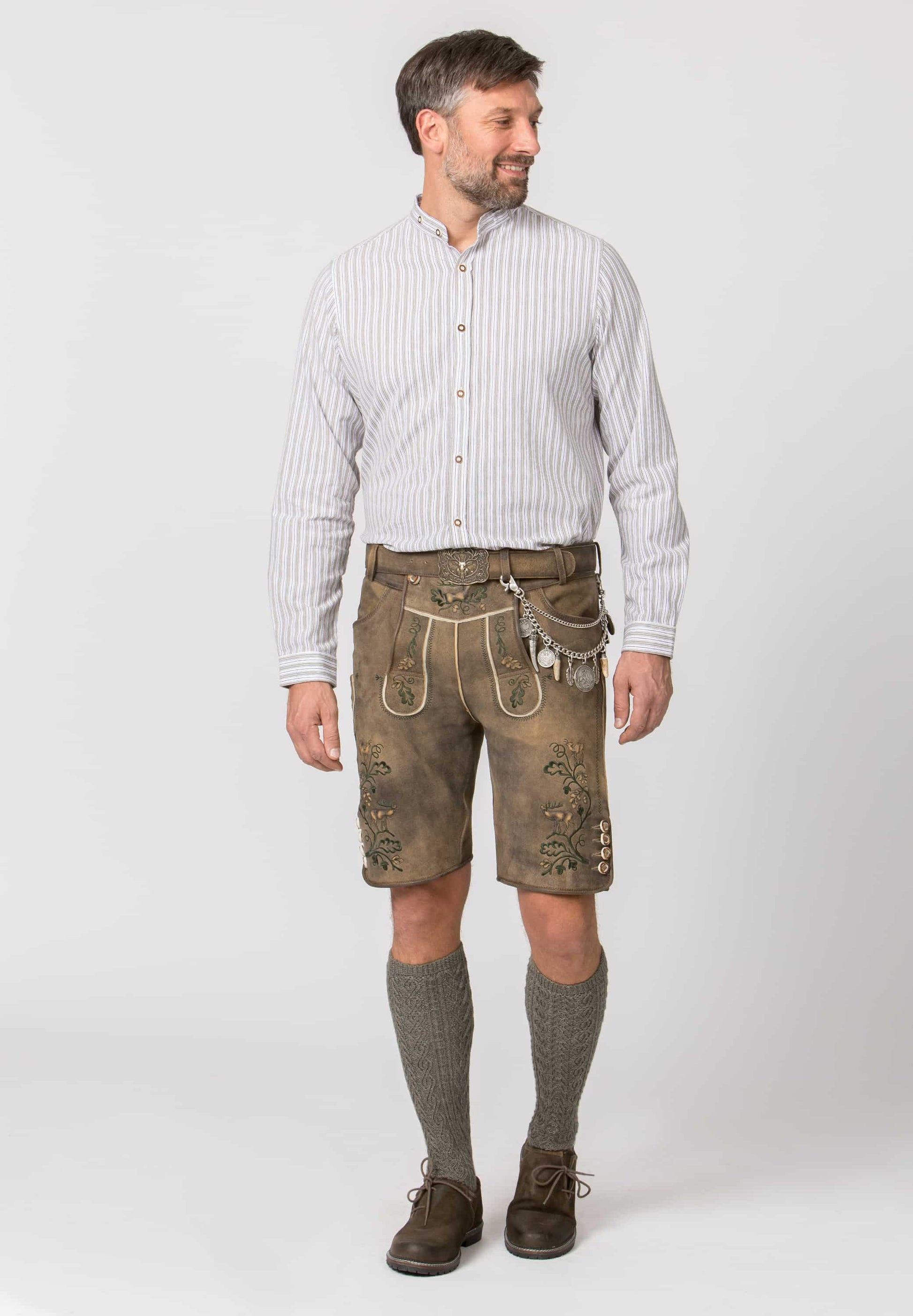 Man wearing traditional Bavarian lederhosen Silver charivari to wear with lederhosen  with various charms on a white background with a white shirt on a white background