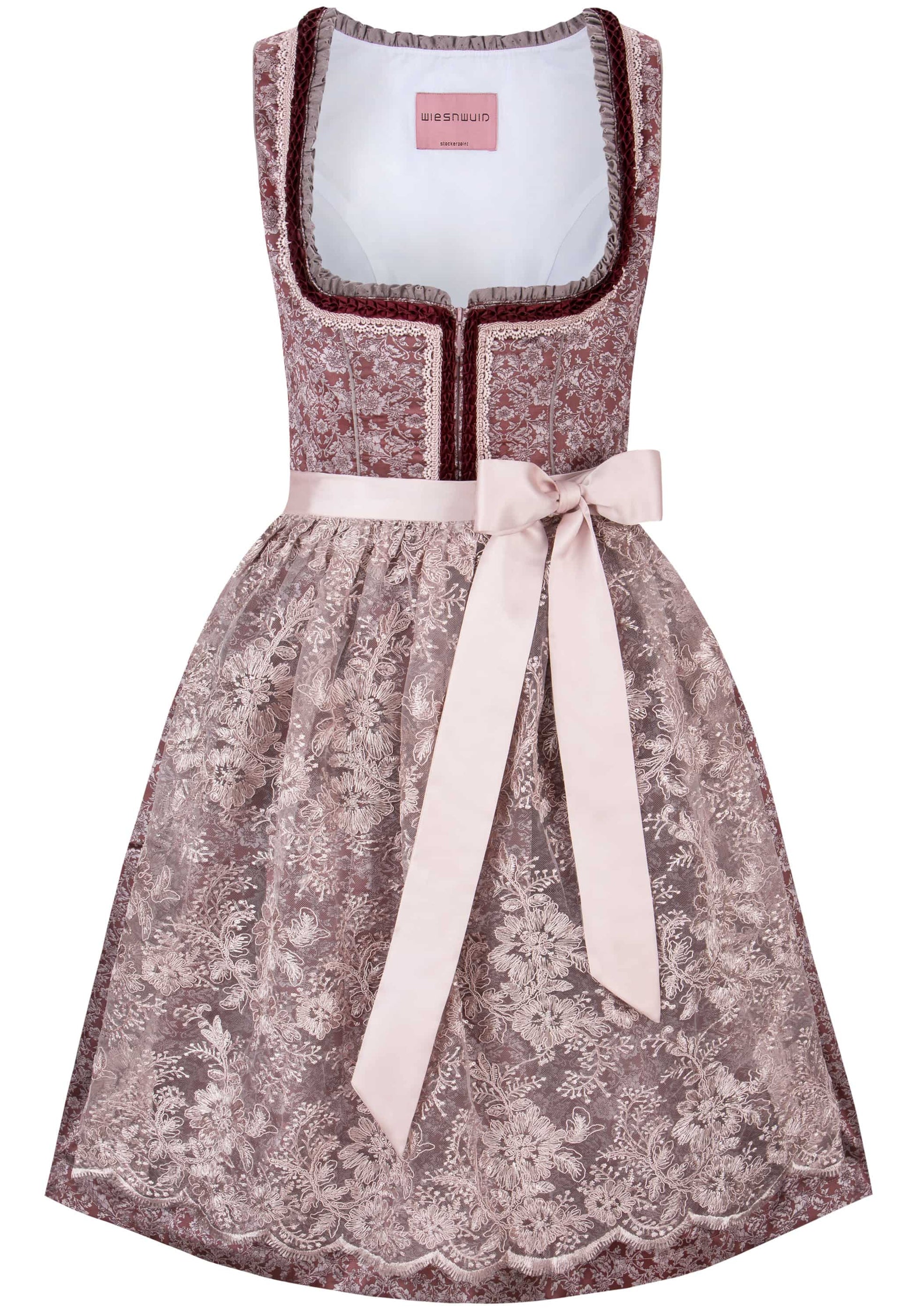 A sleeveless dirndl dress with a dusty rose floral lace pattern, a white inner lining, dark red trim, and a light pink satin waist tie bow, shown on a plain white background.