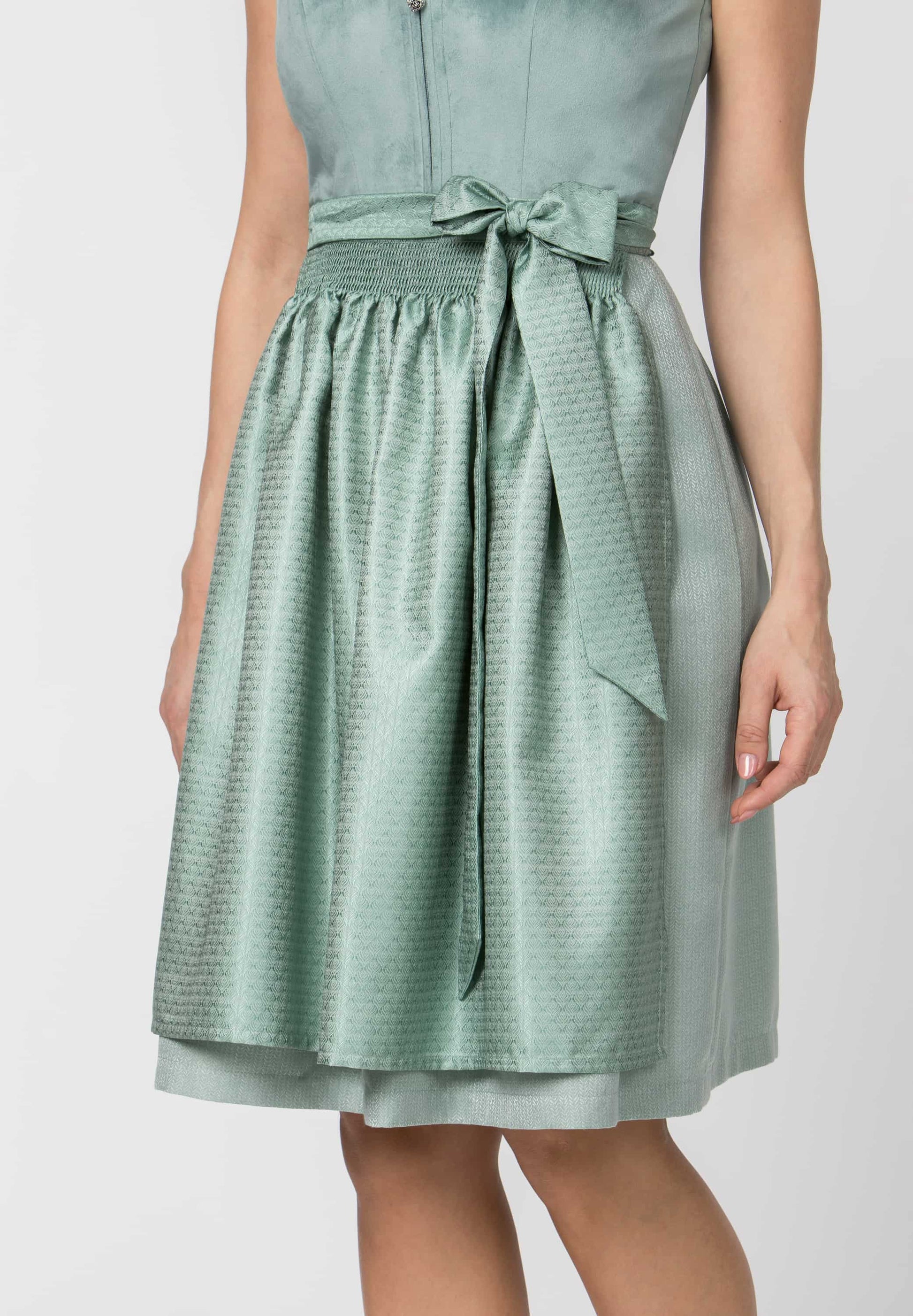 A woman wearing a sleeveless mint green midi dress with a textured pattern, a matching waist tie bow, and a double-layered skirt, shown against a plain light gray background.