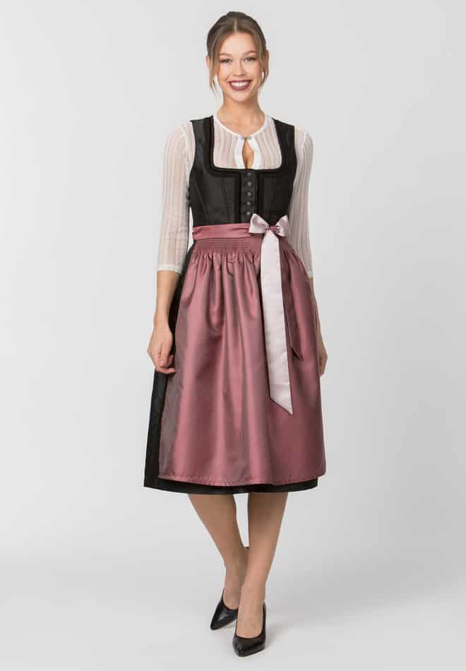 Woman wearing a traditional outfit with a black top and pink skirt on a white background