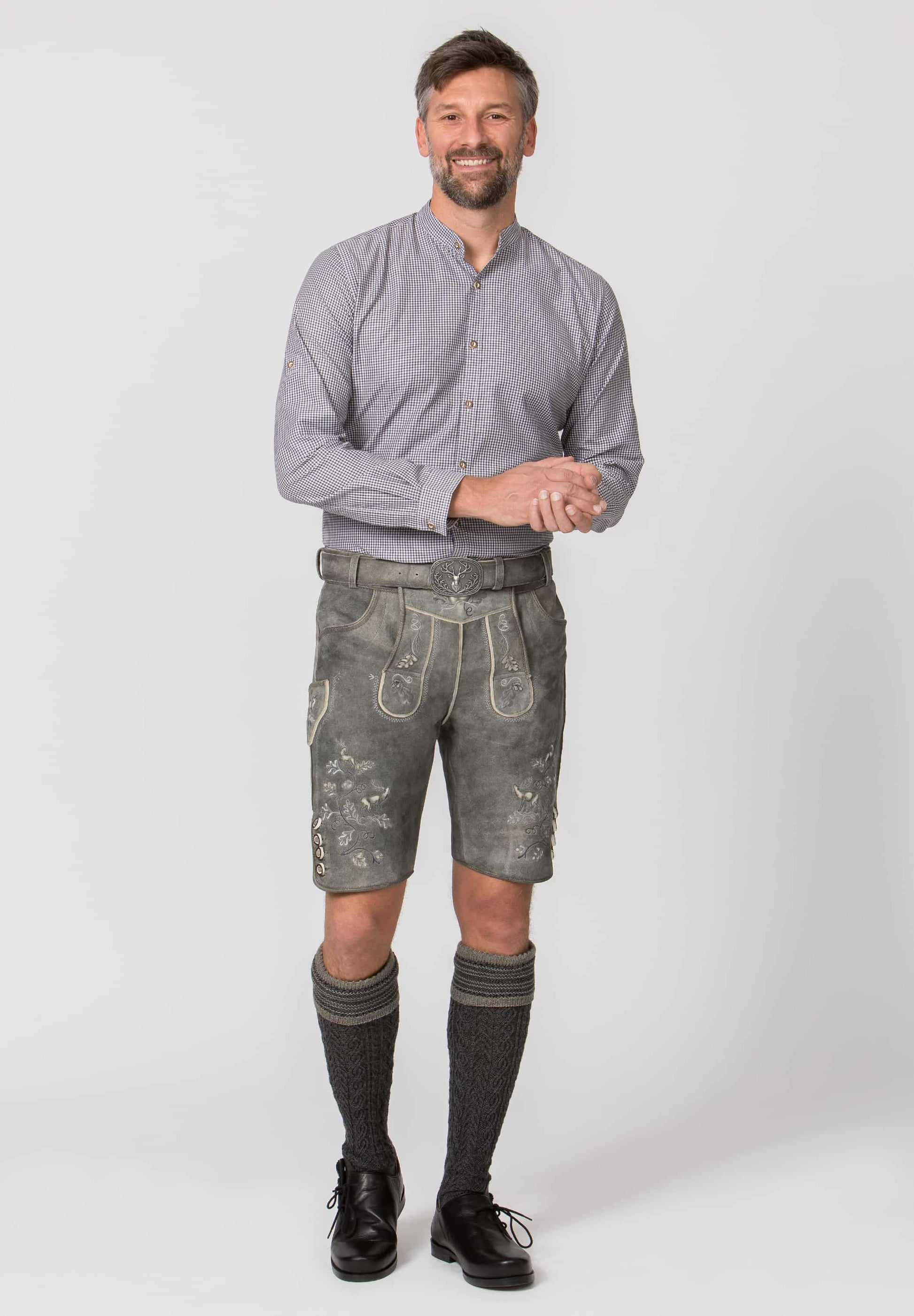 Man wearing a traditional outfit with a gray shirt and patterned shorts on a white background