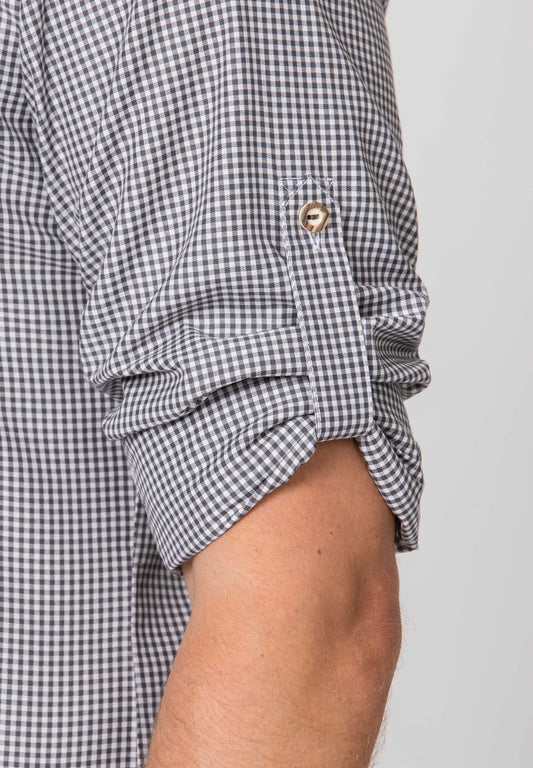 Close-up of a person wearing a black and white checkered shirt with rolled-up sleeves on a plain background