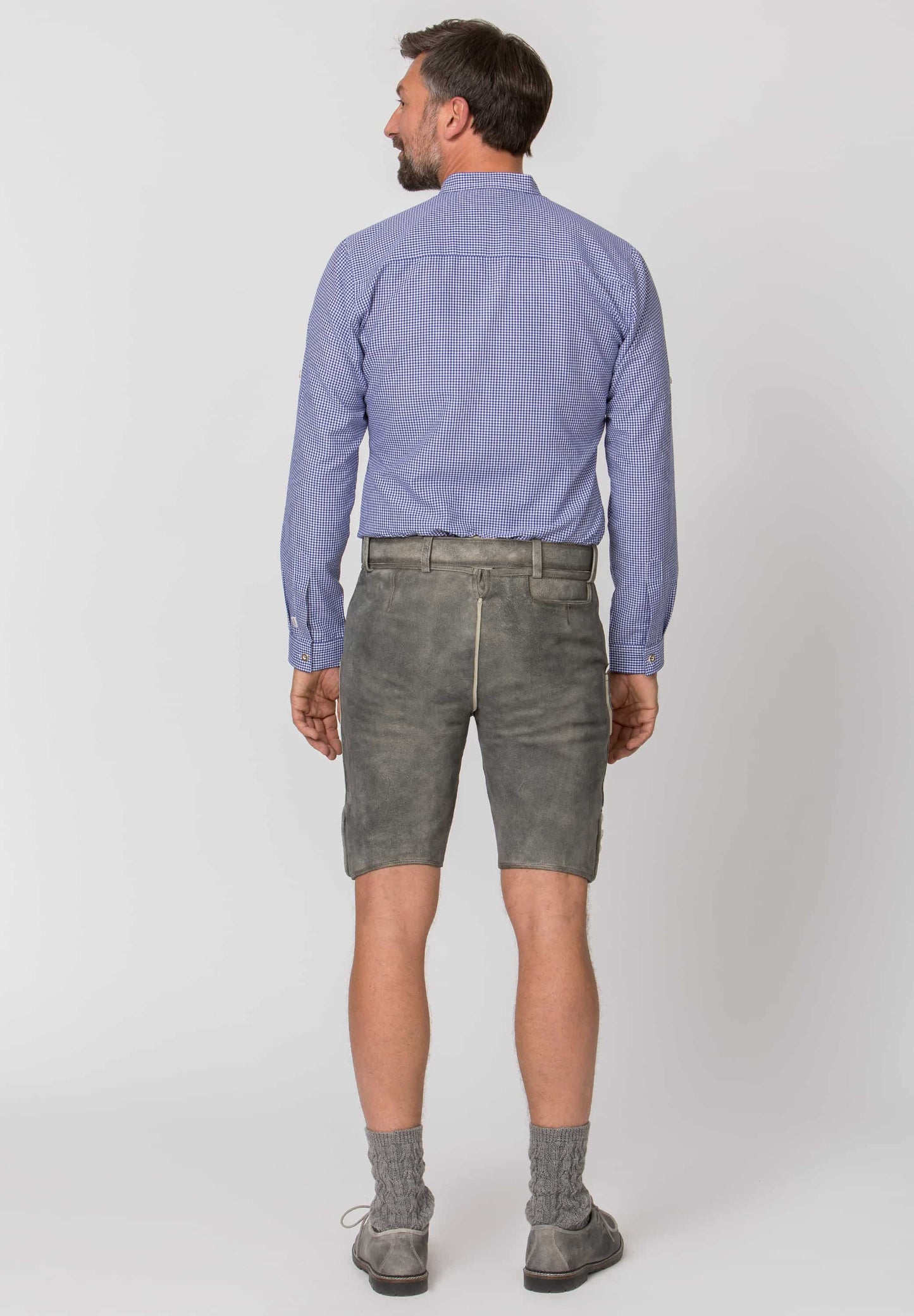 Man wearing a light blue shirt and gray shorts on a white background