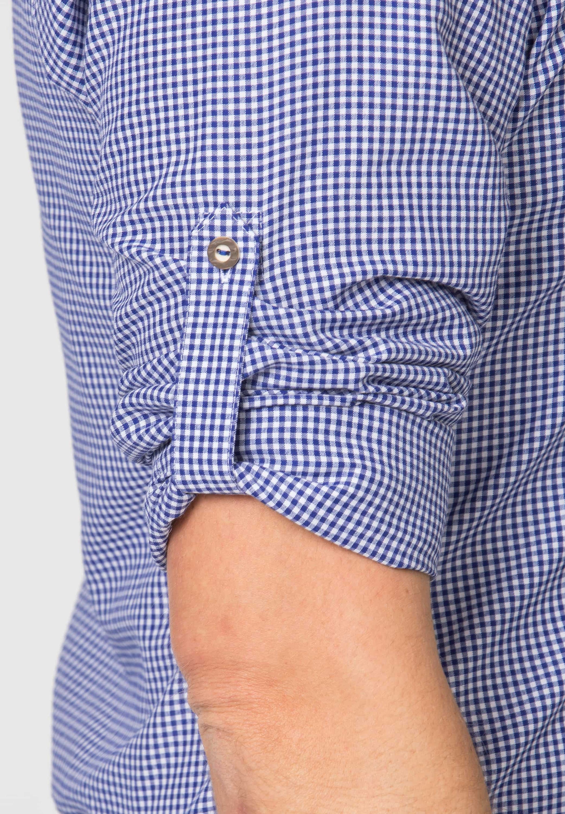 Close-up of a person wearing a blue and white checkered shirt with rolled-up sleeves.