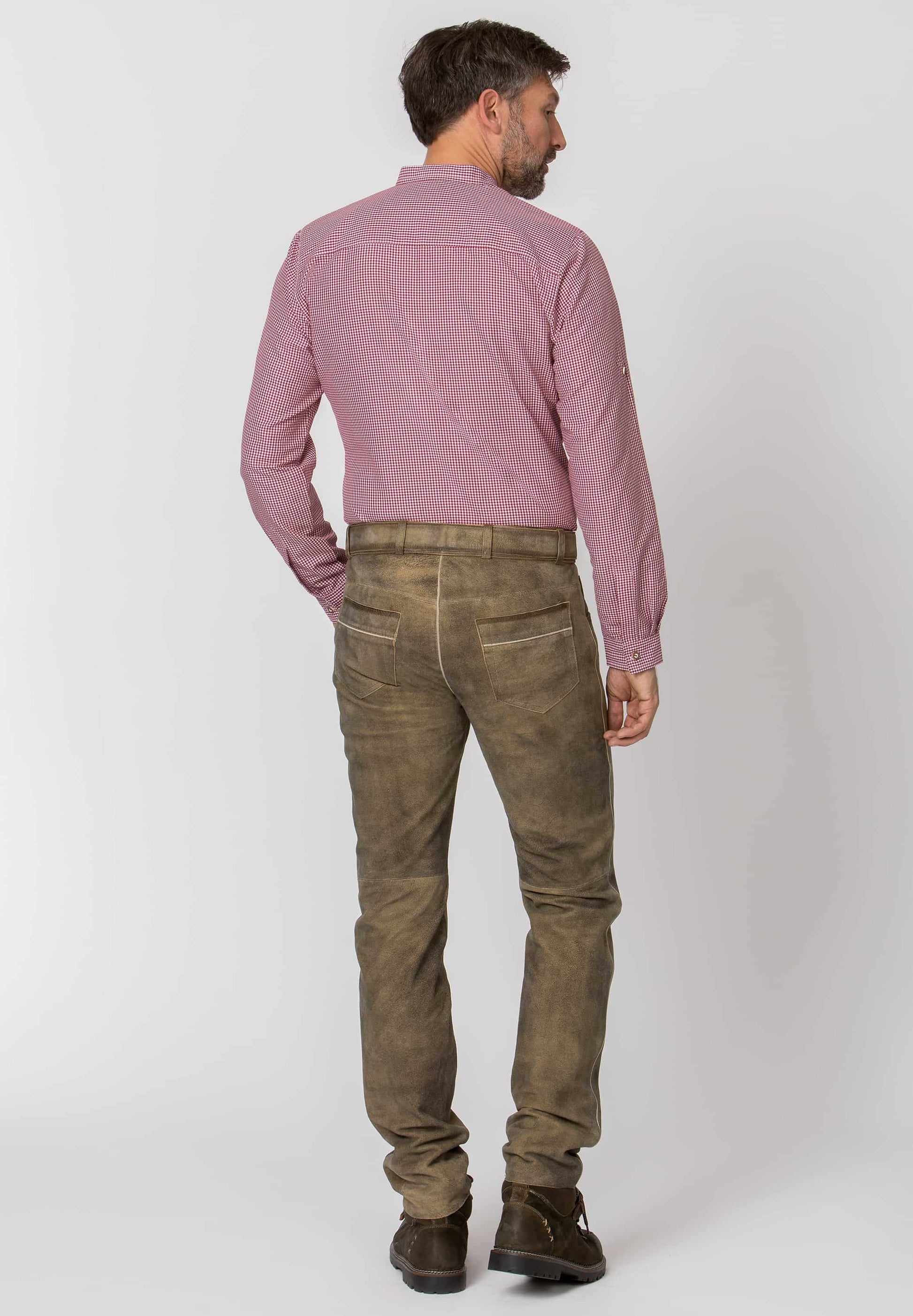 Man wearing a pink shirt and brown pants on a white background