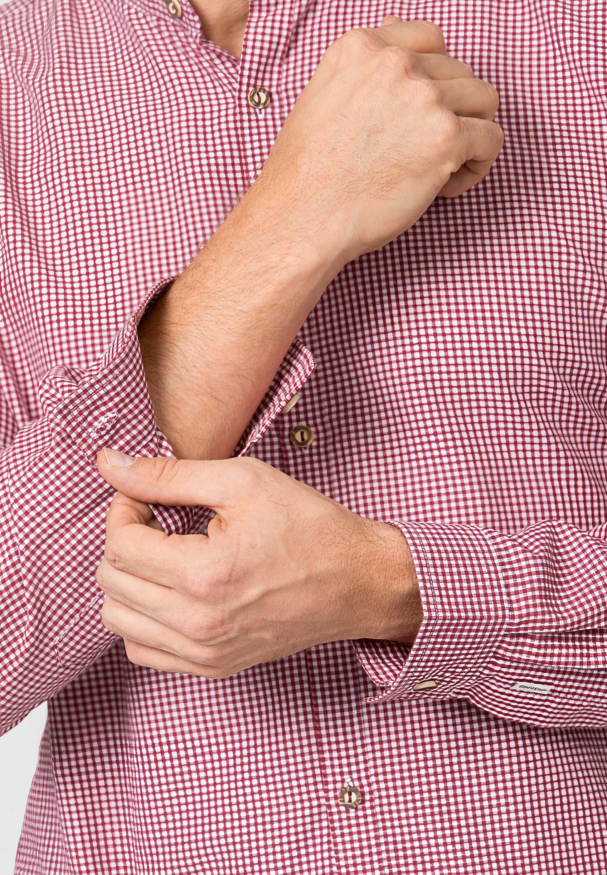 Person wearing a red and white checkered shirt with rolled-up sleeves.