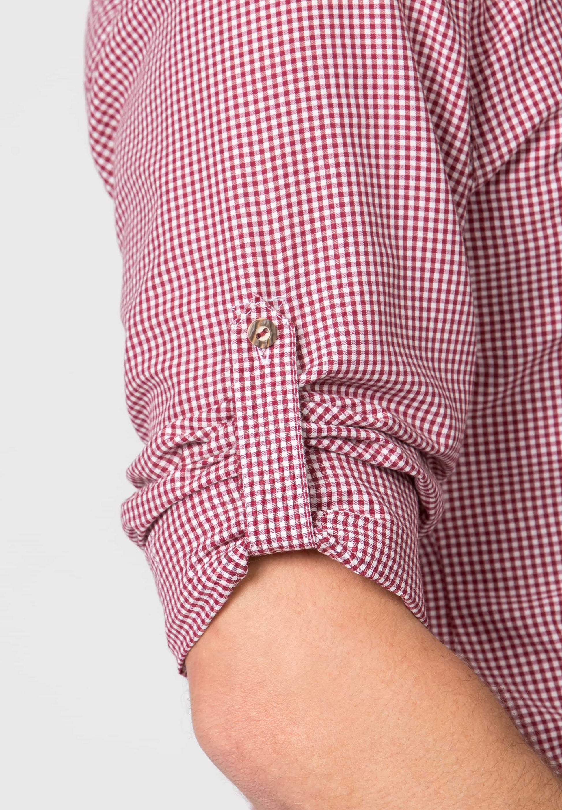 Close-up of a red and white checkered shirt with rolled-up sleeve on a light gray background