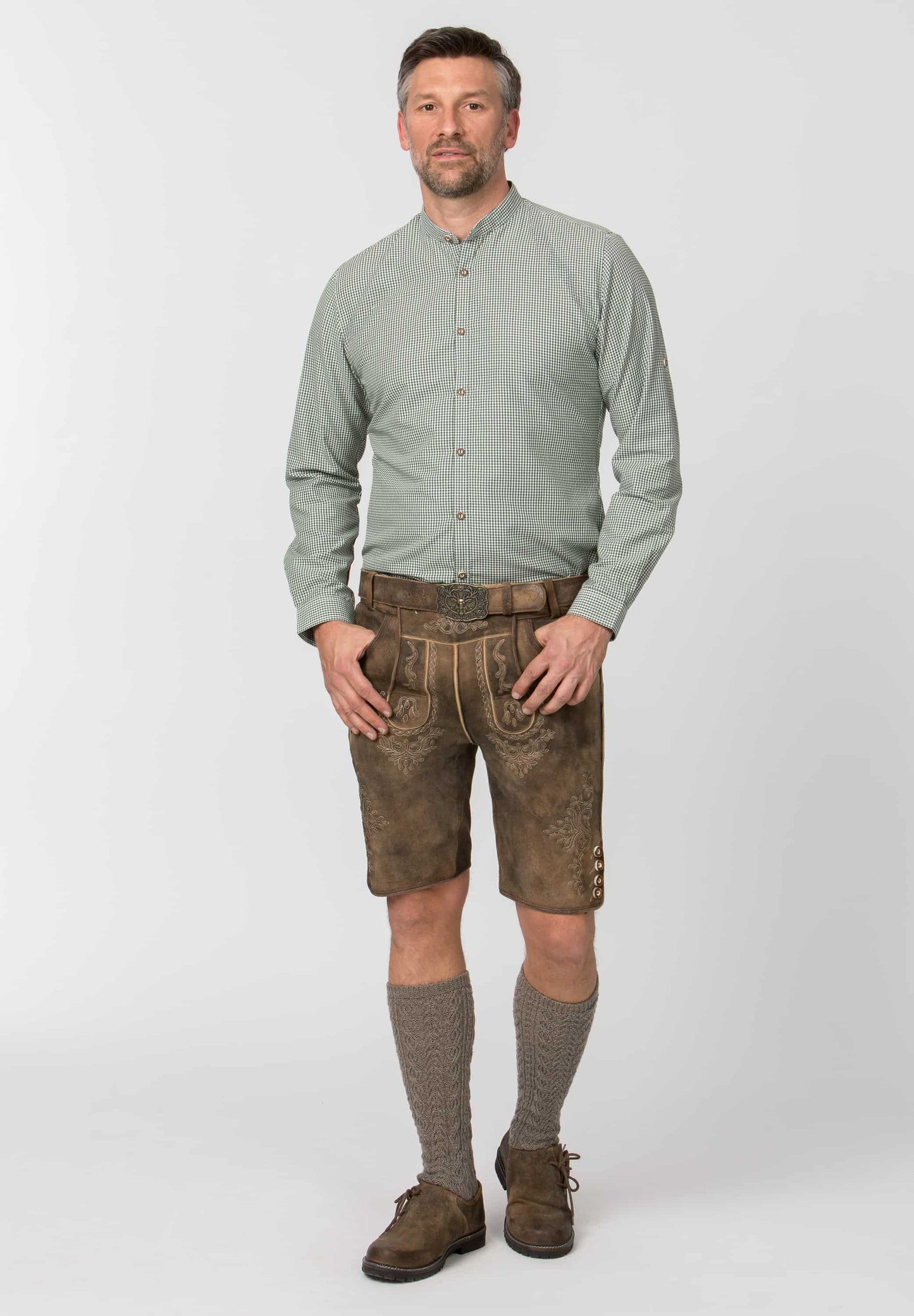 Man wearing a light green shirt, brown shorts, and brown shoes on a white background