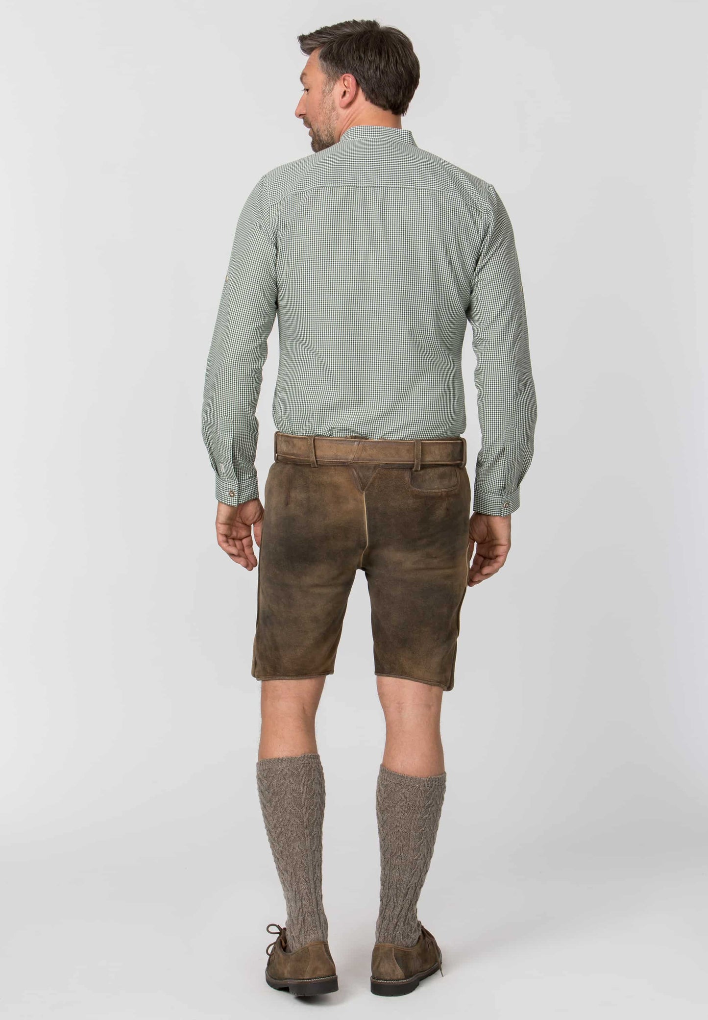 Man wearing a light green shirt, brown shorts, and knee-high socks on a white background