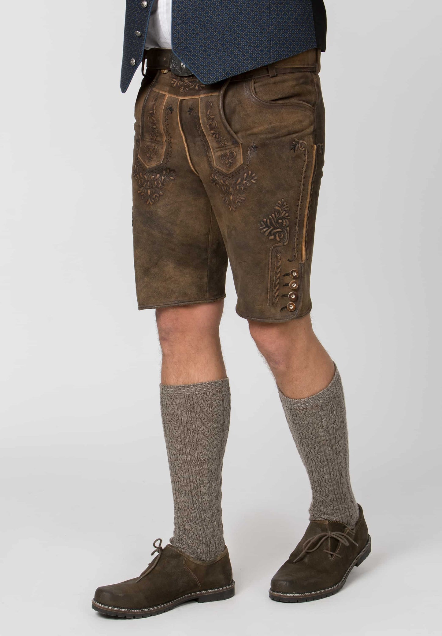 Brown leather shorts with decorative stitching worn by a person on a white background