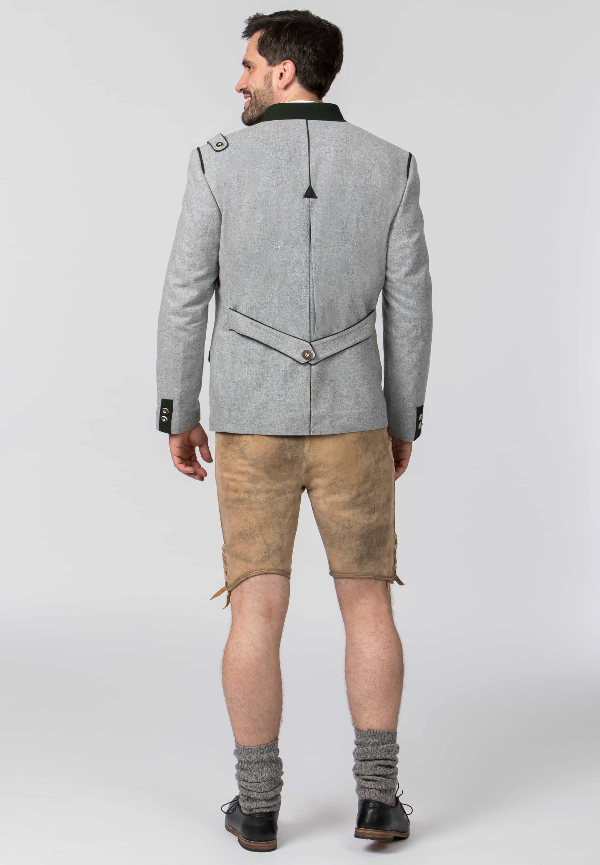 A man shown from the back wearing a light gray blazer with a black collar, tan shorts, gray socks, and black shoes, photographed against a plain light gray studio background.
