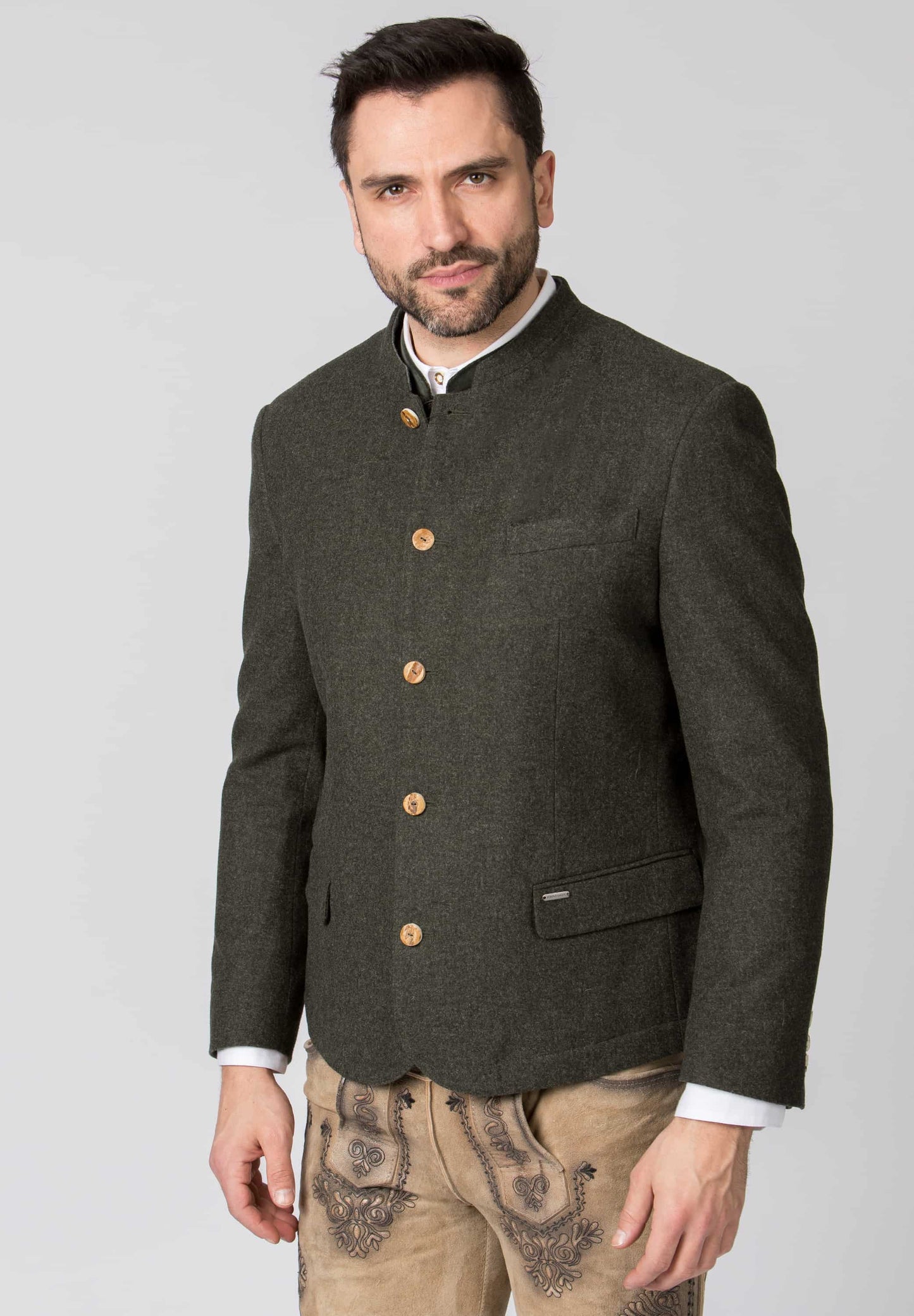 Man wearing a dark green jacket with brown buttons on a light gray background
