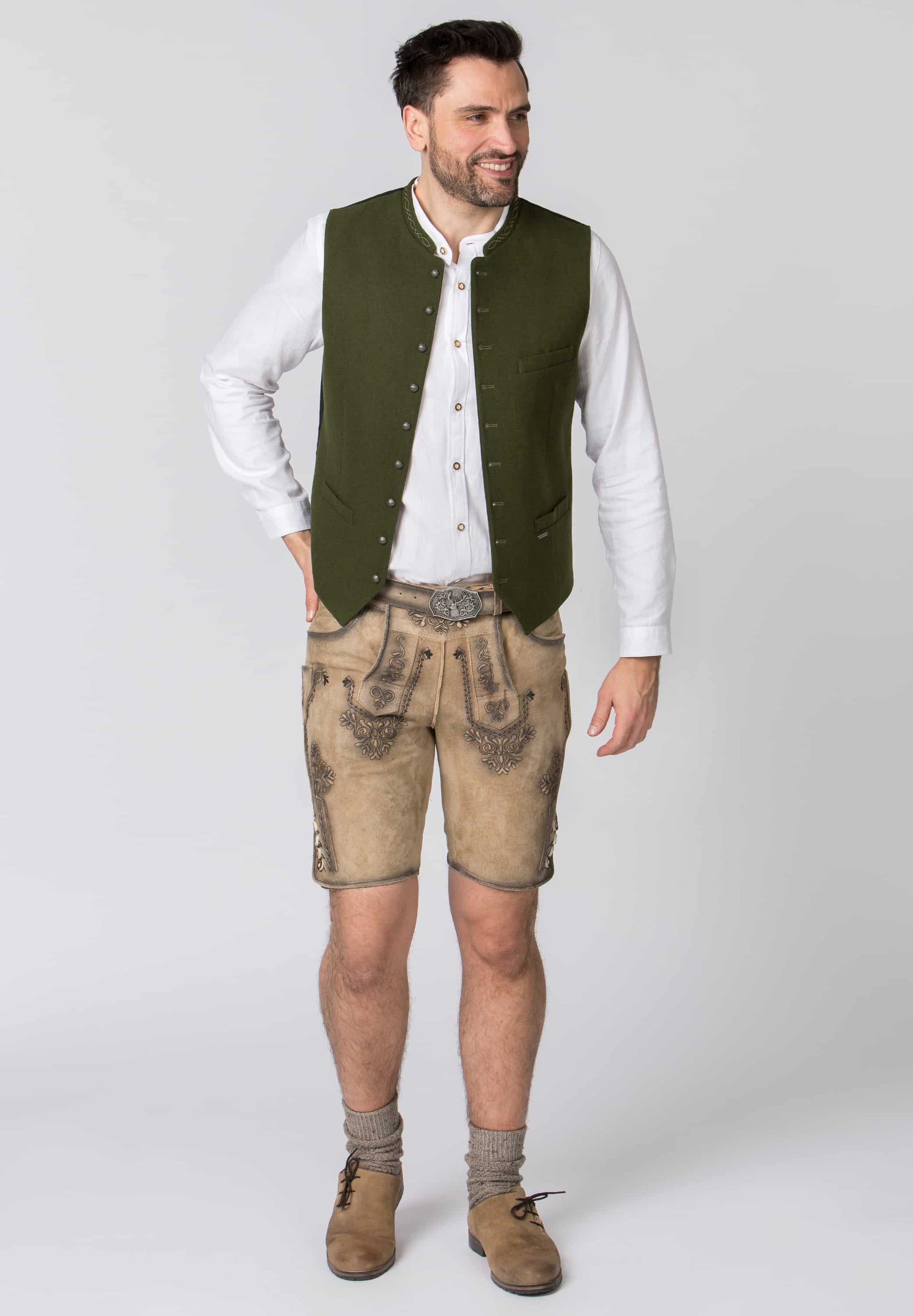 Man wearing traditional German outfit with green vest and beige pants on a white background