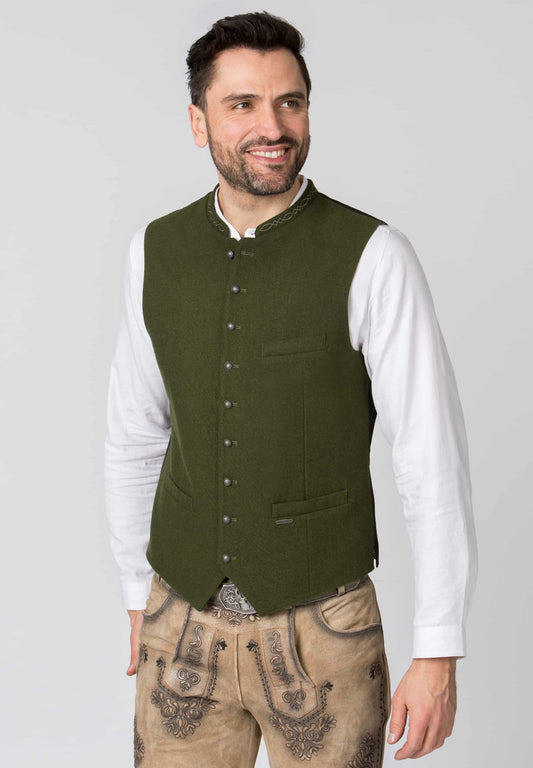 Man wearing a green vest over a white shirt with a plain background