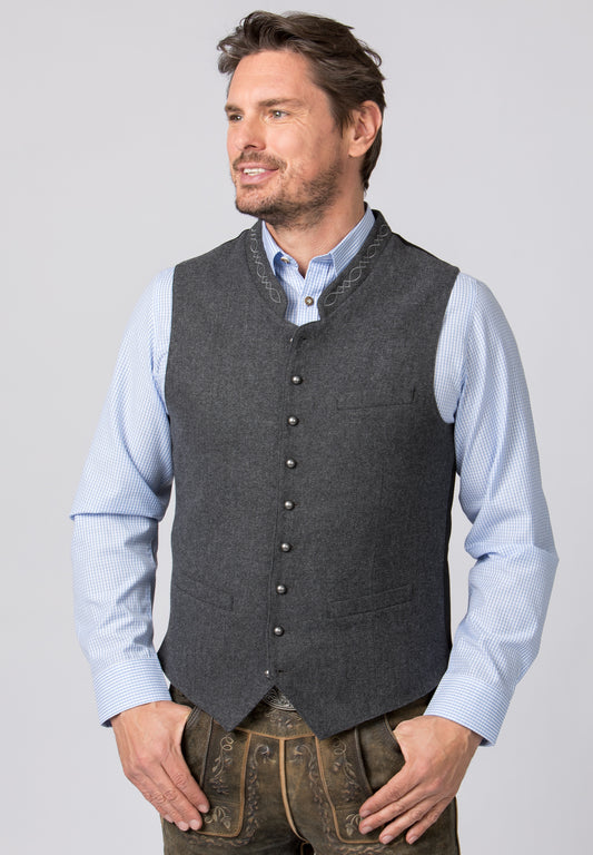 A close up of a  man wearing a gray traditional costume vest with a stand-up collar, buttoned front, and embroidery details. He is also wearing a blue shirt.